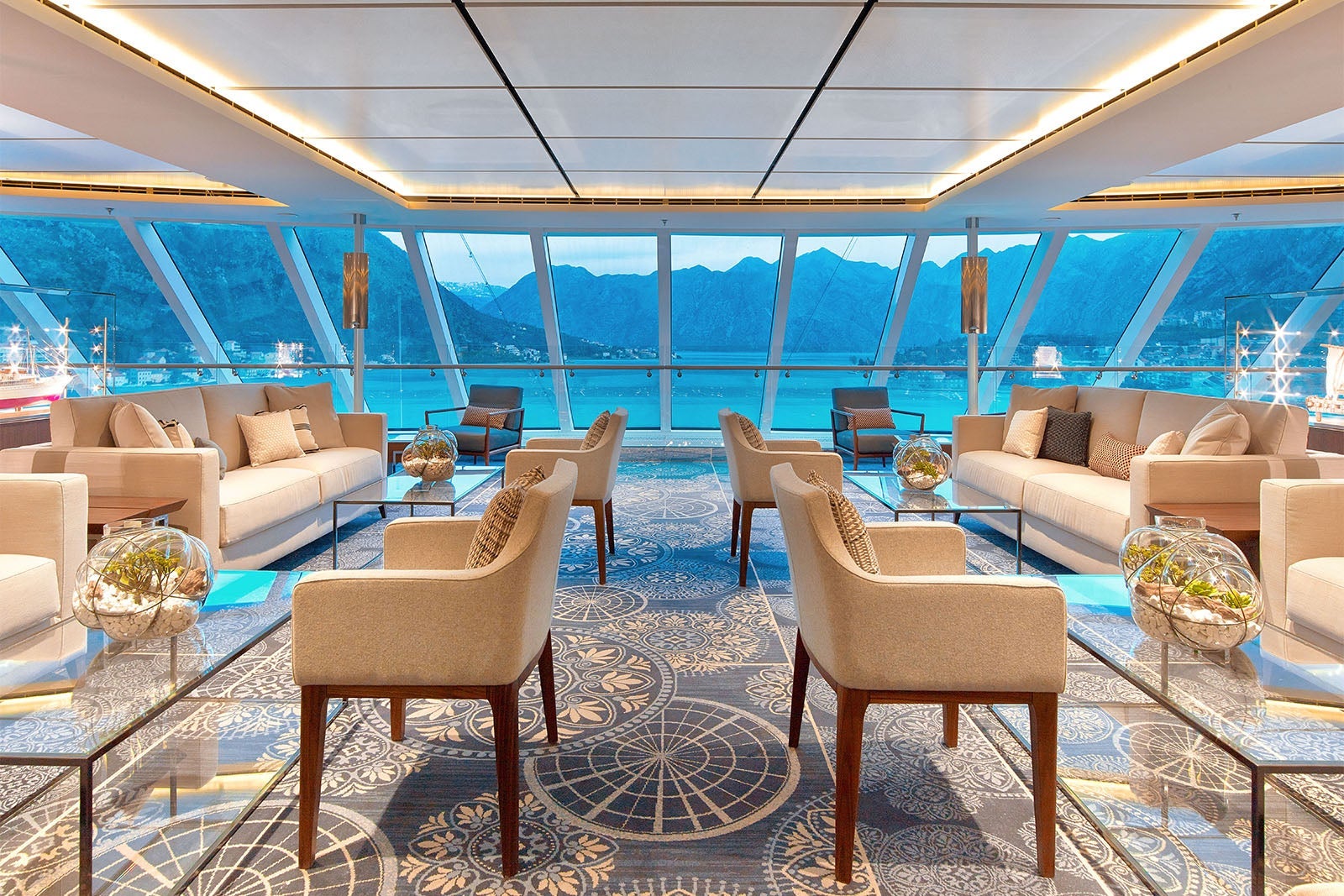 Cruise ship lounge with floor to ceiling windows and beige furniture