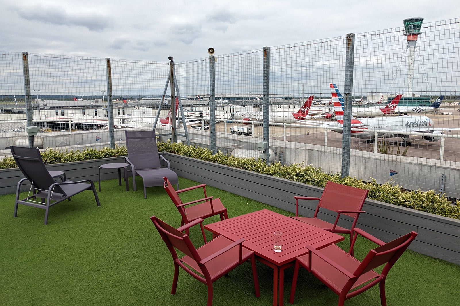 Rooftop garden with seating areas looking over runway with parked airplanes