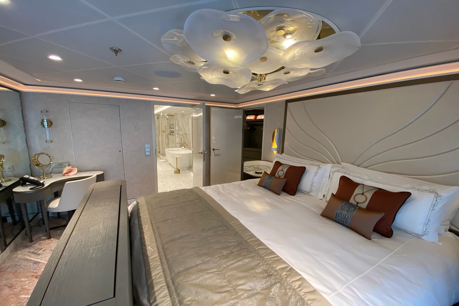 A view of a suite including a king-sized bed, a vanity and a bathroom in the distance