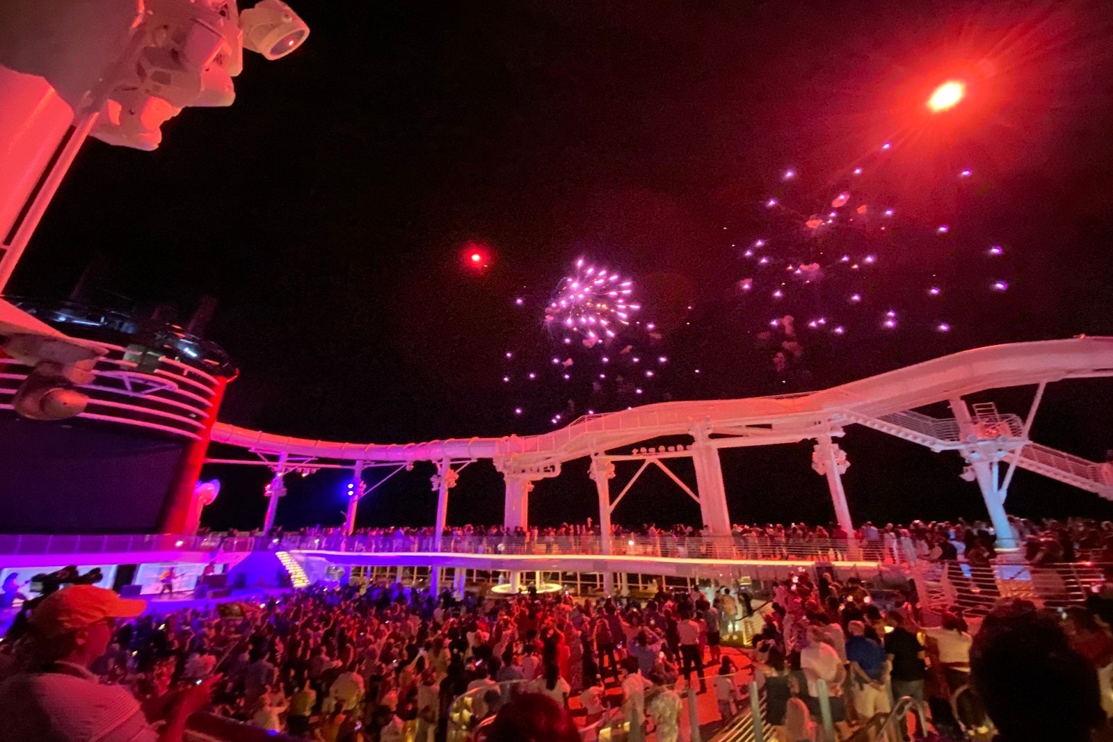 Passengers crowding the pool deck under fireworks on a Disney Cruise Line ship