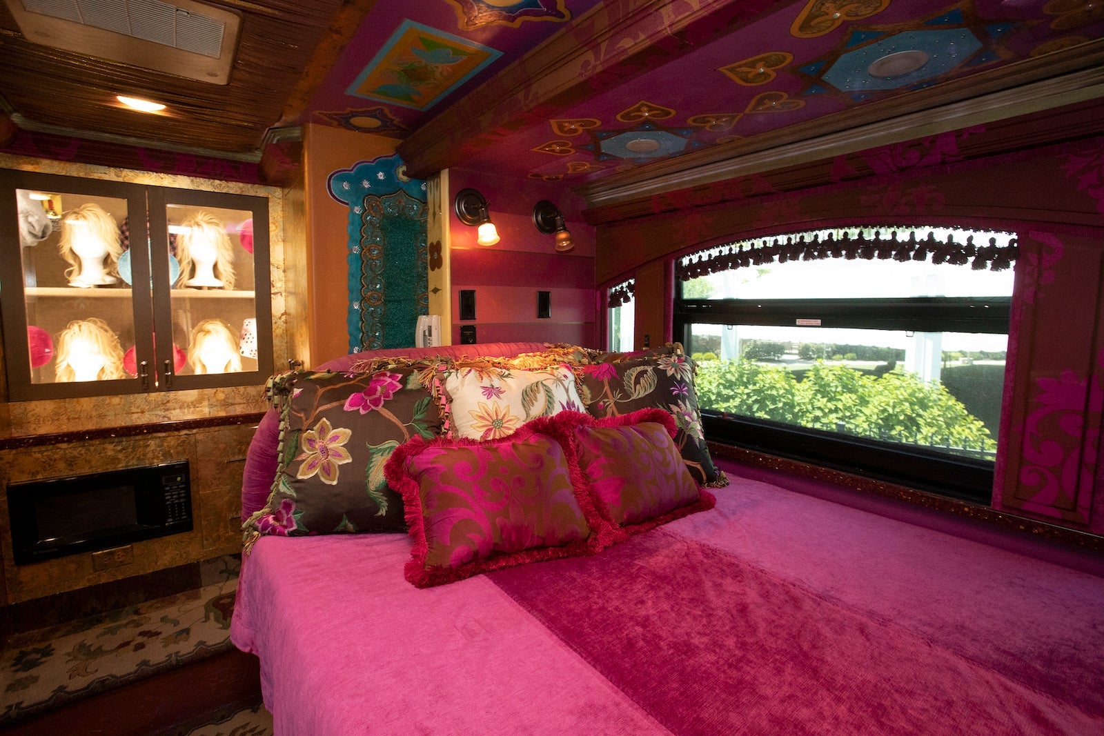 pink bedding on tour bus bed with glass case of Dolly Parton's blonde wigs