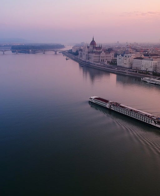 A river cruise going past the Hungarian Parliament Building in an early morning.
