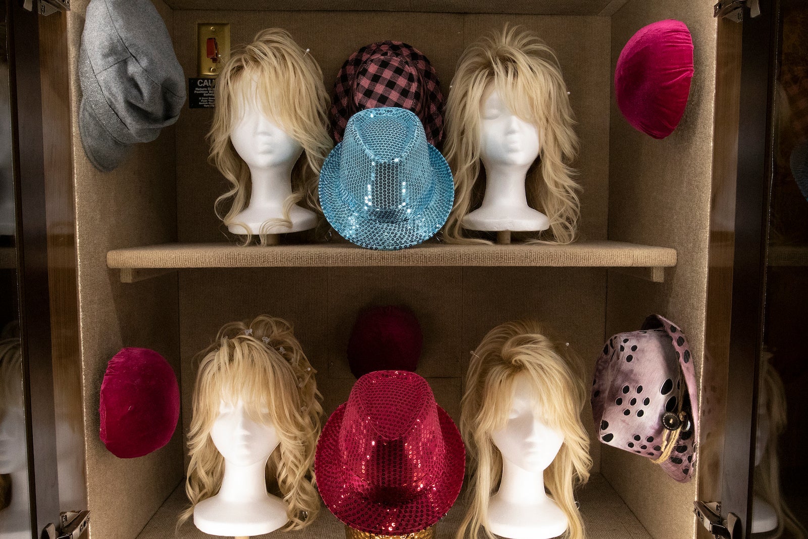 shelf with glittery hats and Dolly Parton's blonde wigs
