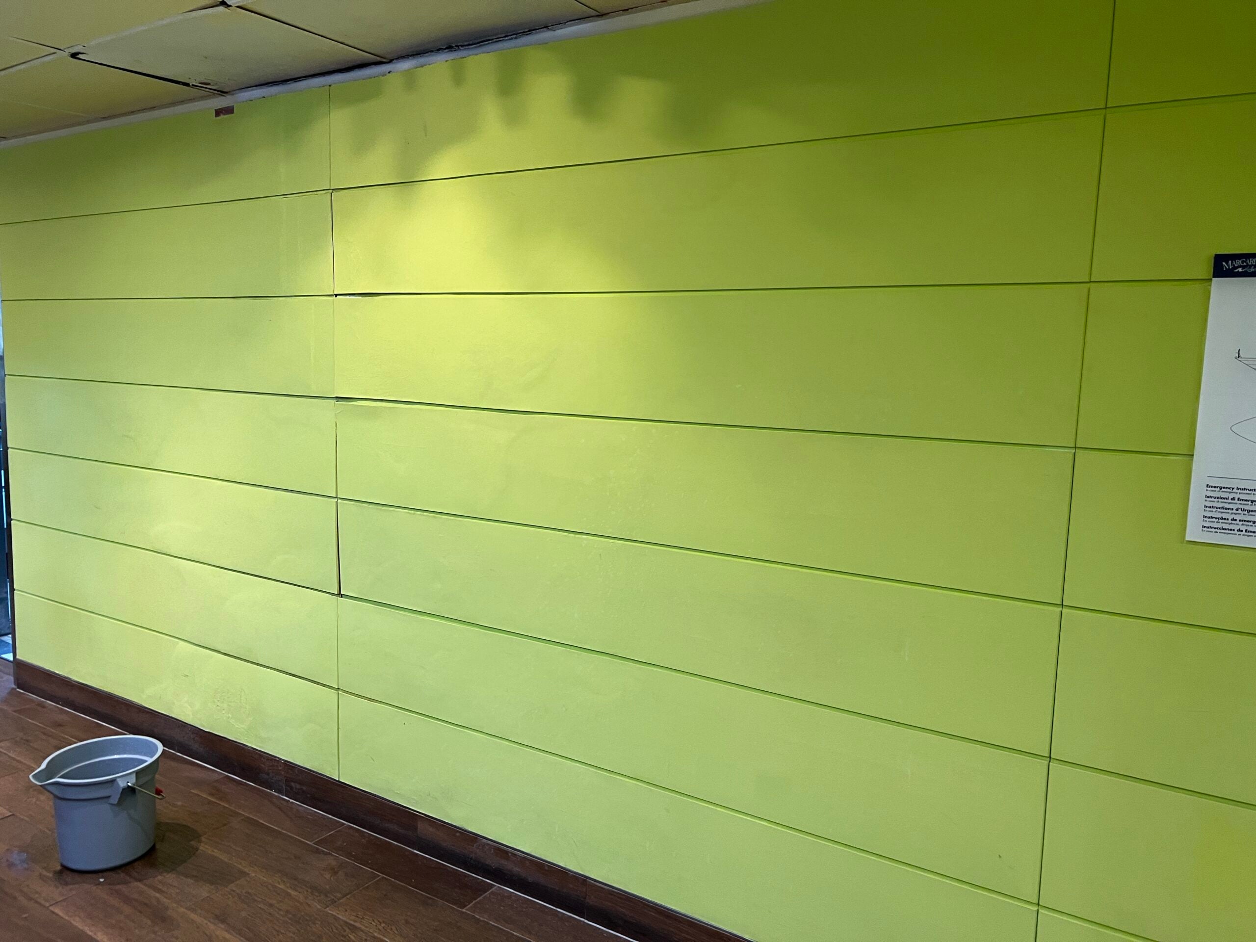 Green wall with a bucket on the ground for a ceiling leak