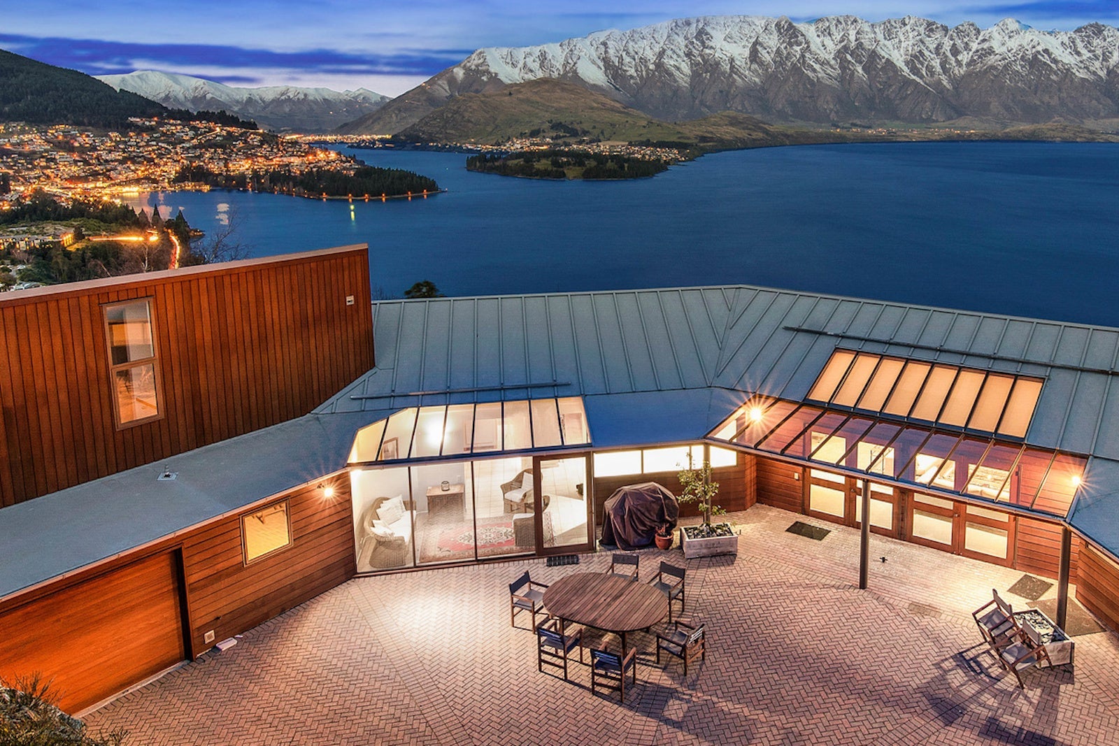 Aerial photo of house with courtyard in front of bay and snow-capped mountains
