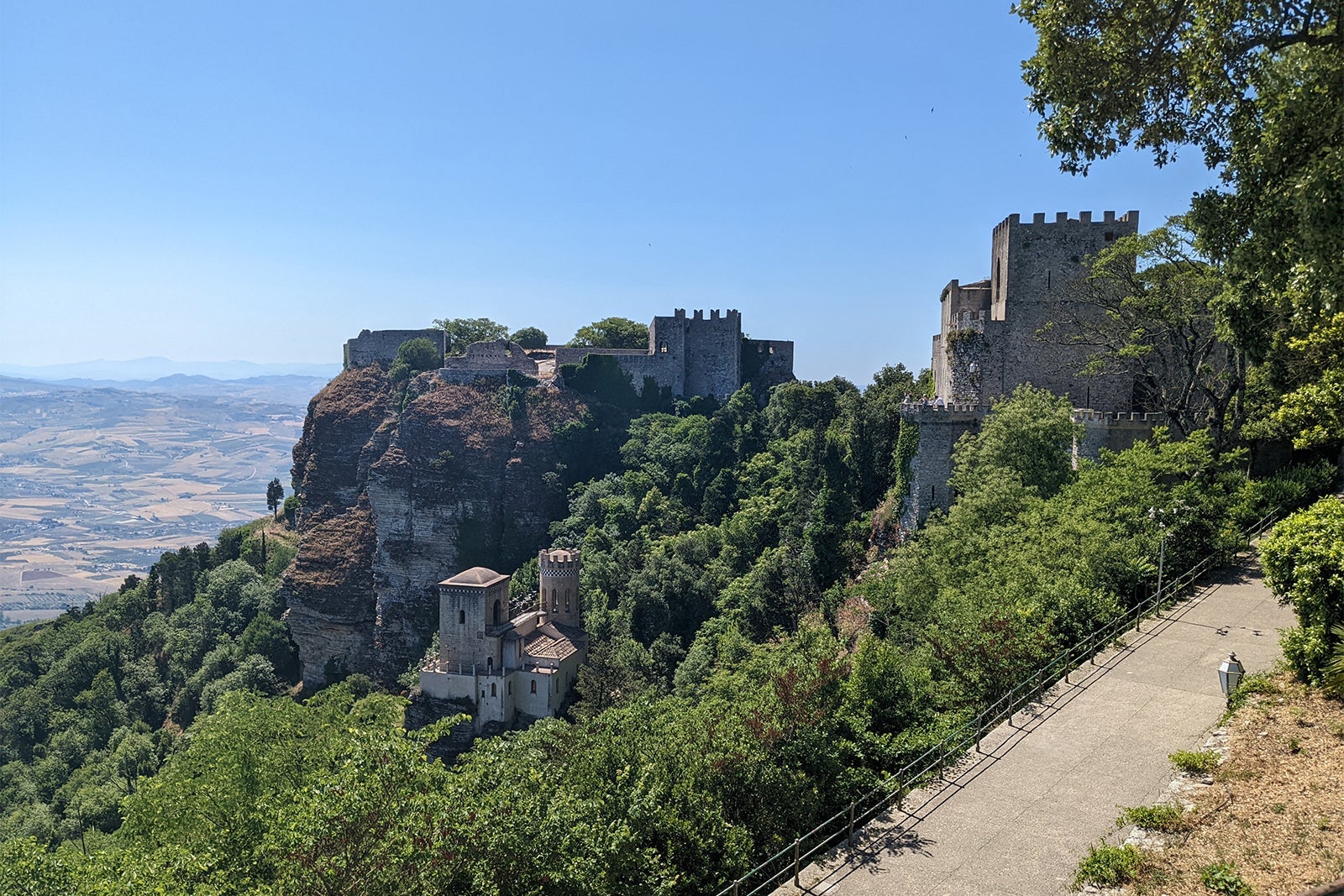 Stone castle in Erice on cliff surrounded by greenery