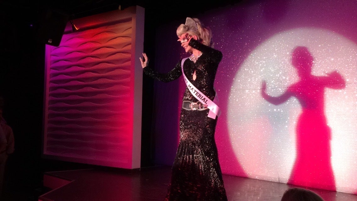 Drag queen on stage in black dress with sash