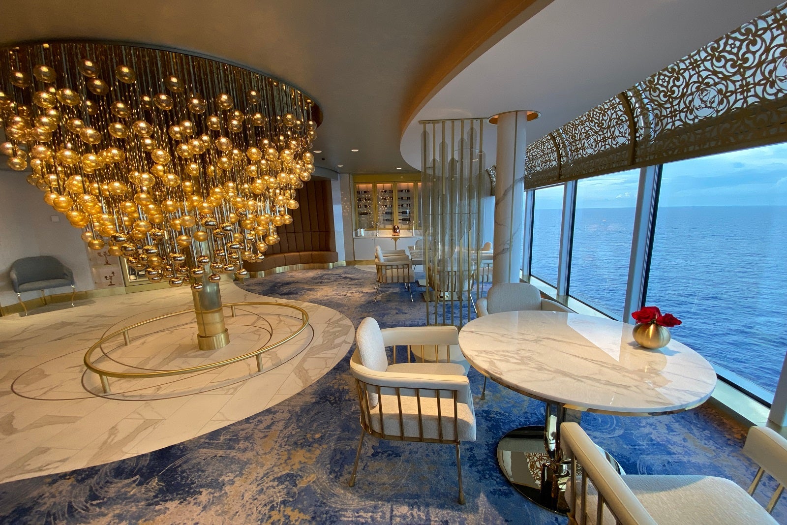 A light, airy restaurant with marble-topped tables, blue carpeting and a treelike light fixture