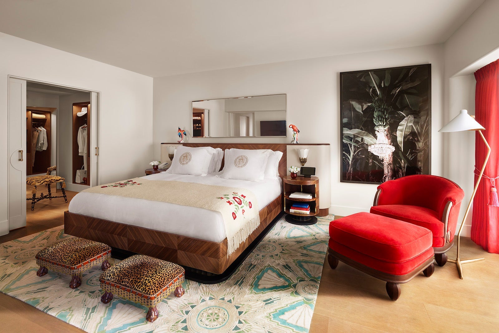 well-appointed hotel room with red chair and large bed