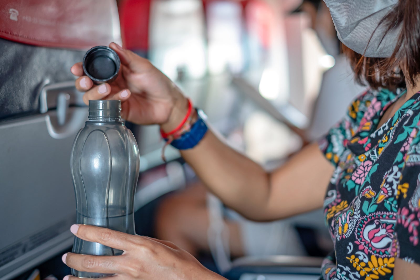 woman uses refillable water bottle on plane