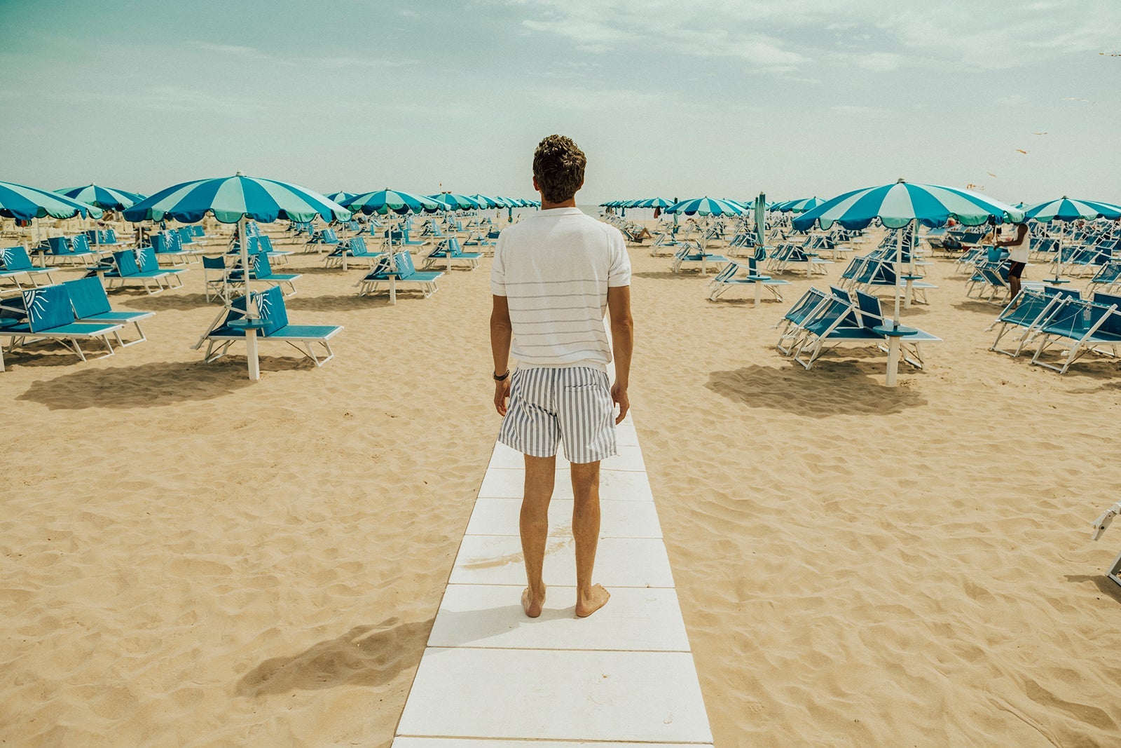 A man standing on a walkway at a European beach