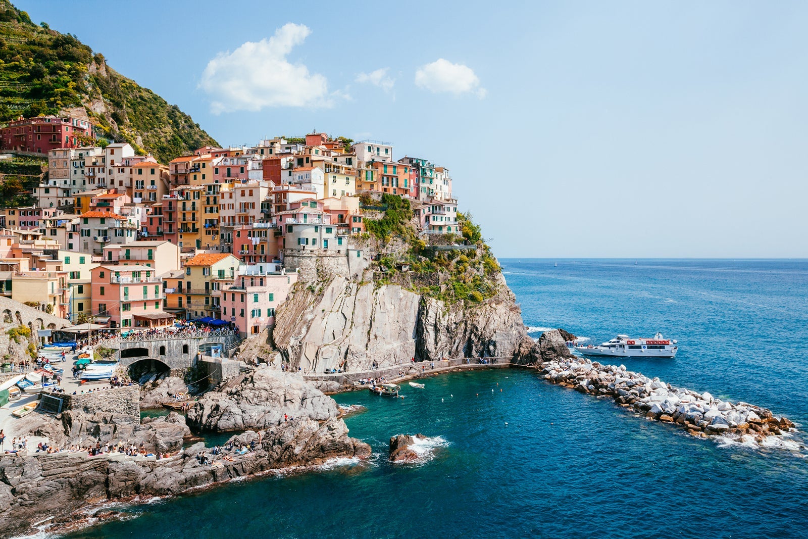 Colorful buildings sit atop a cliff overlooking the blue water in Italy's Cinque Terre