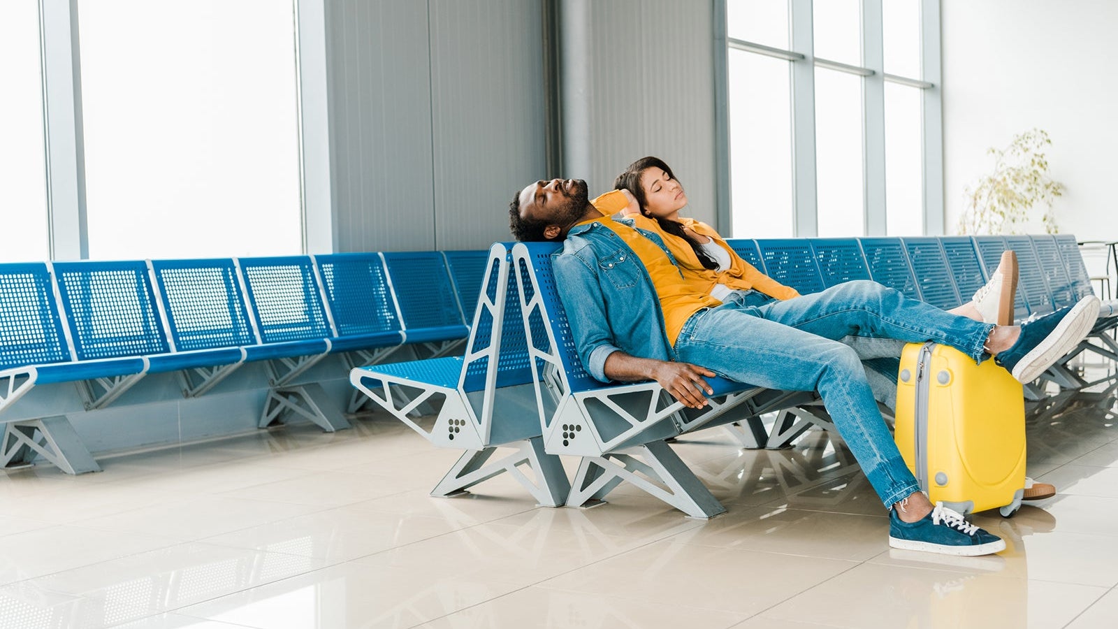 tired african american couple sleeping in departure lounge in airport