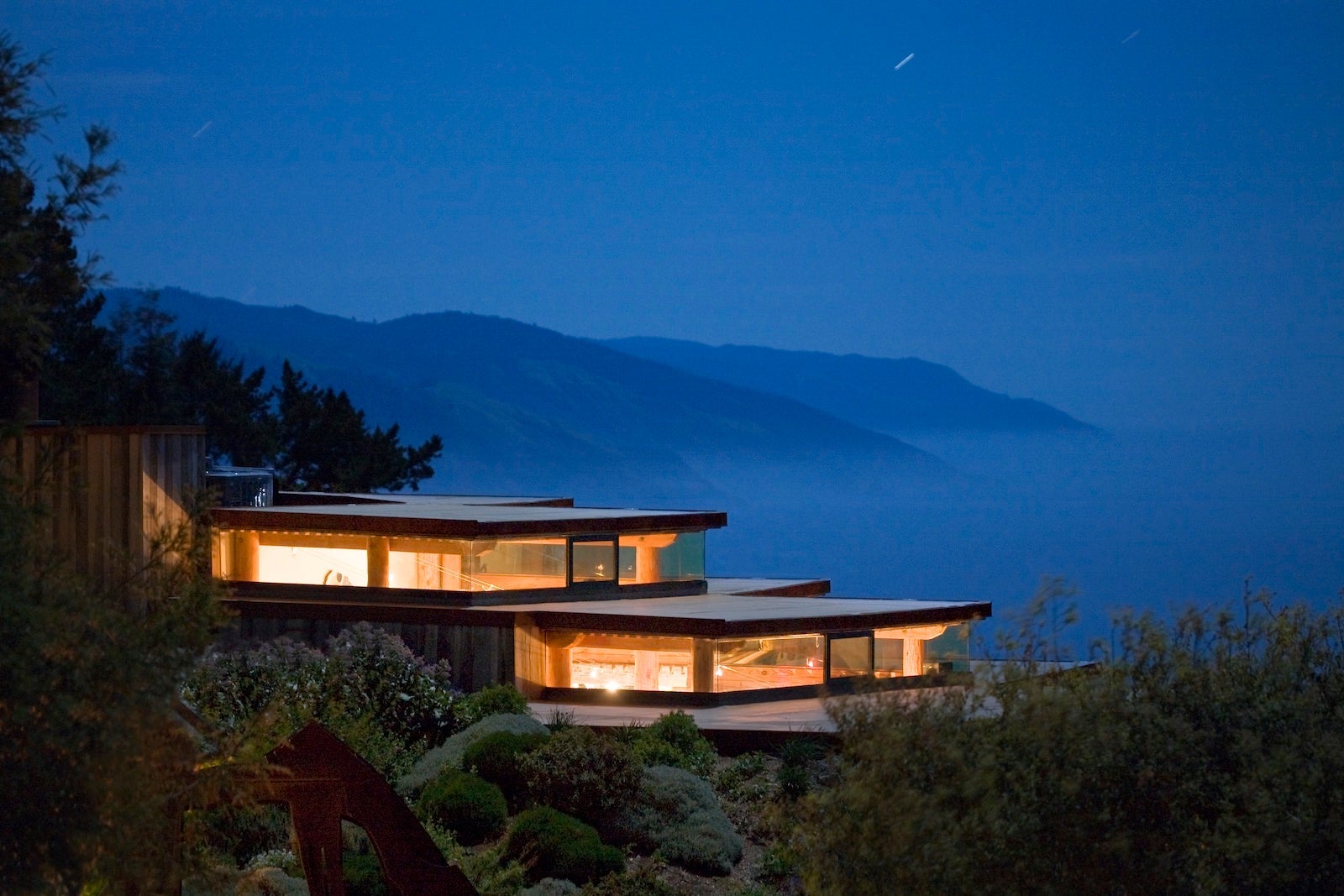 view of glowing glass hotel with mountains in the distance