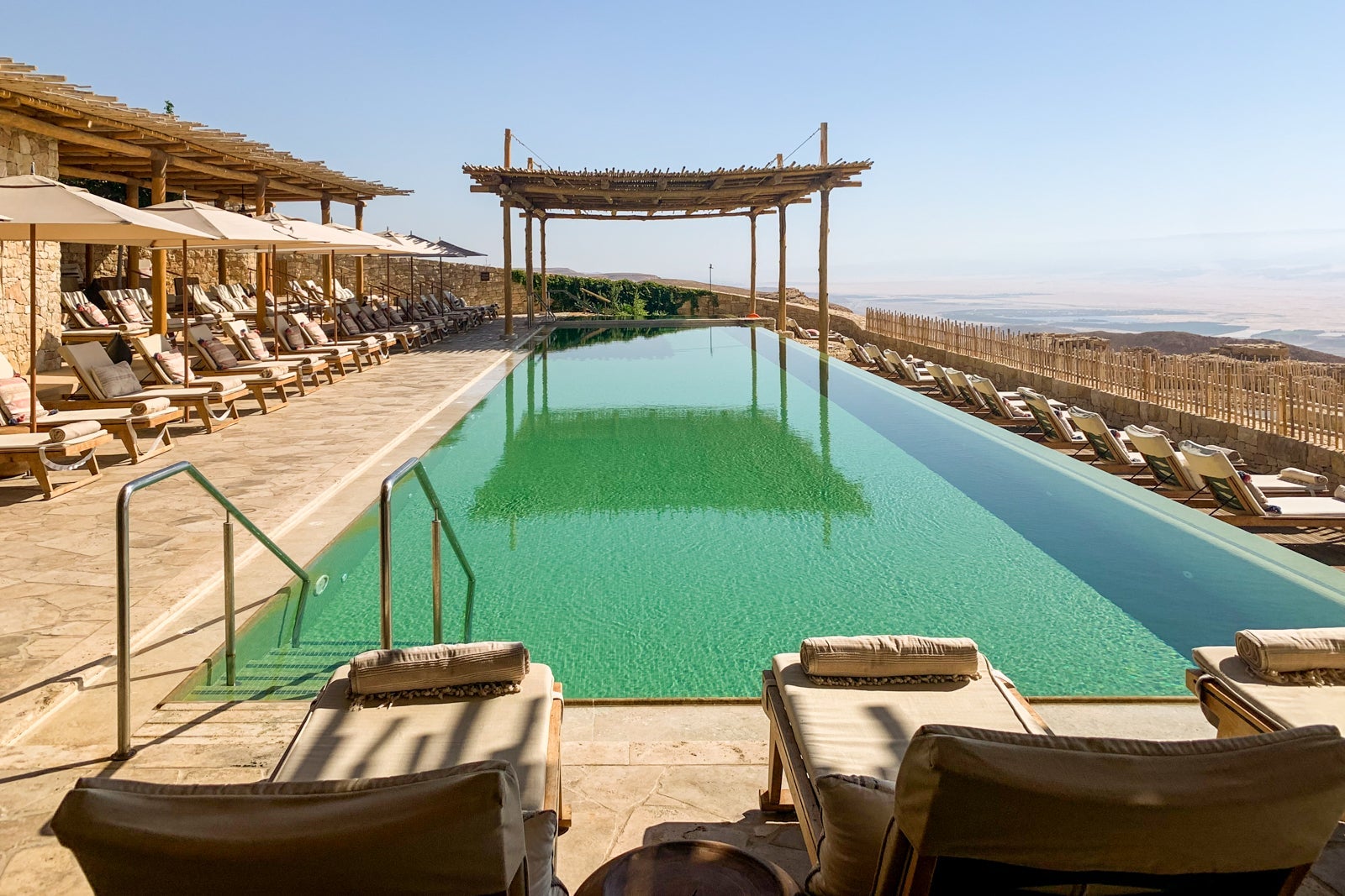 A hotel pool surrounded by desert with mountains in the distance