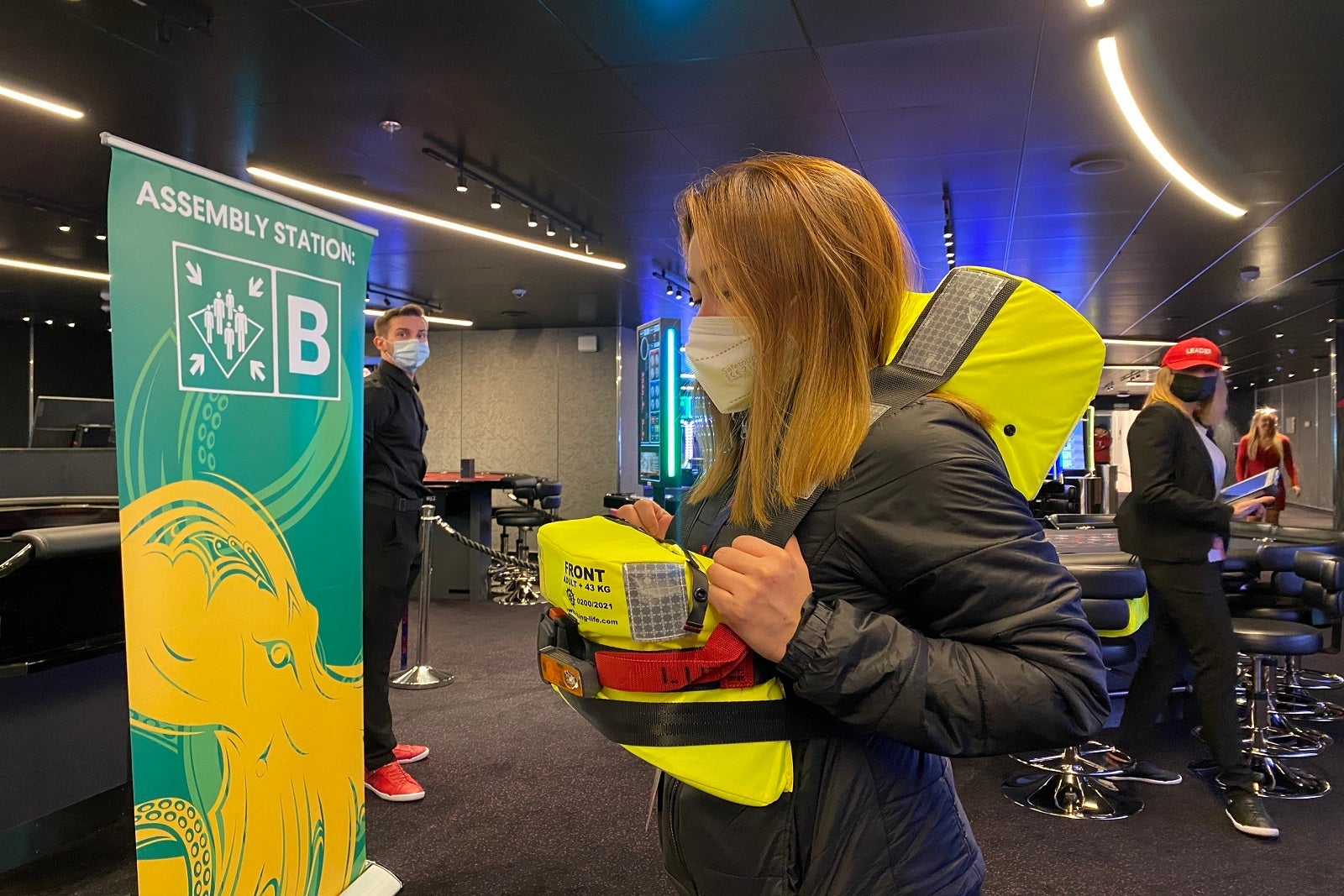 A crew member demonstrates how to put on a life jacket