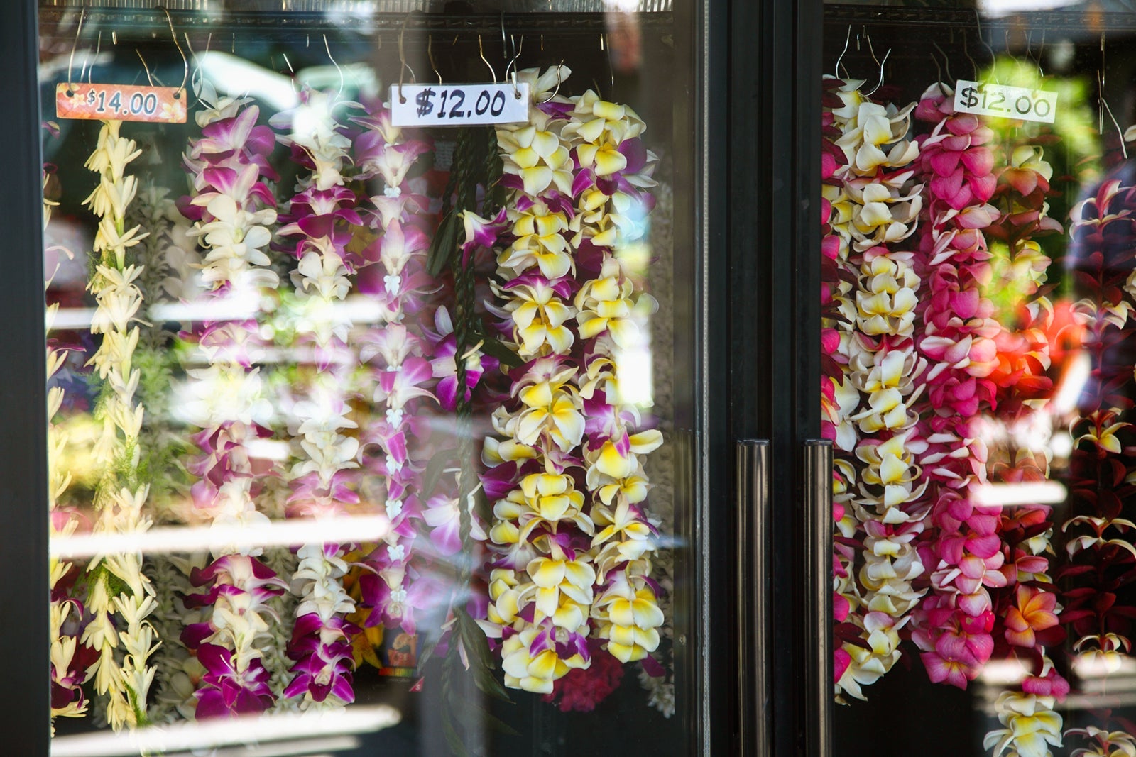 Flower leis hanging in a shop window in Hawaii