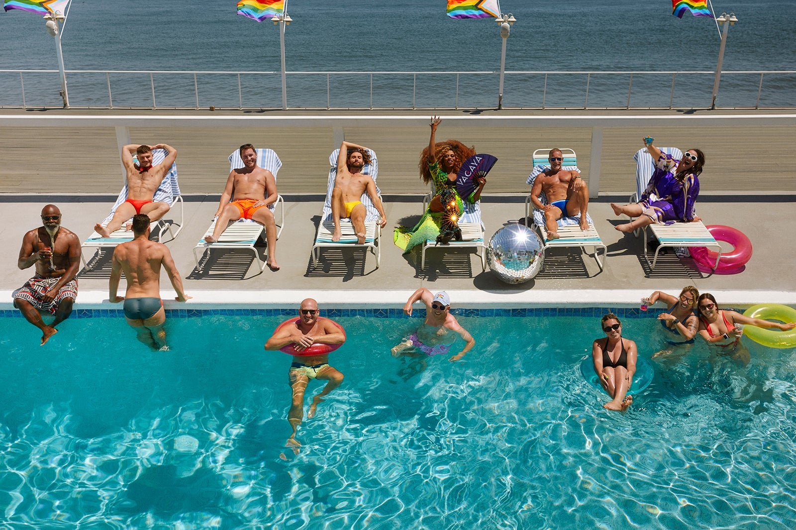 Men sitting on sun loungers and floating in the pool on a cruise ship during a VACAYA cruise