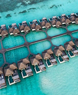 overwater bungalows sitting on top of turquoise blue water connected by walkways