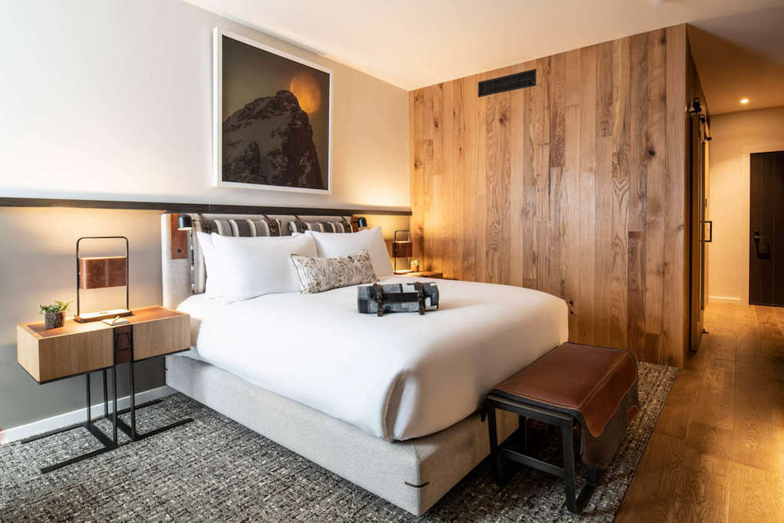 hotel room with wood wall, bed and photo of mountain over bed