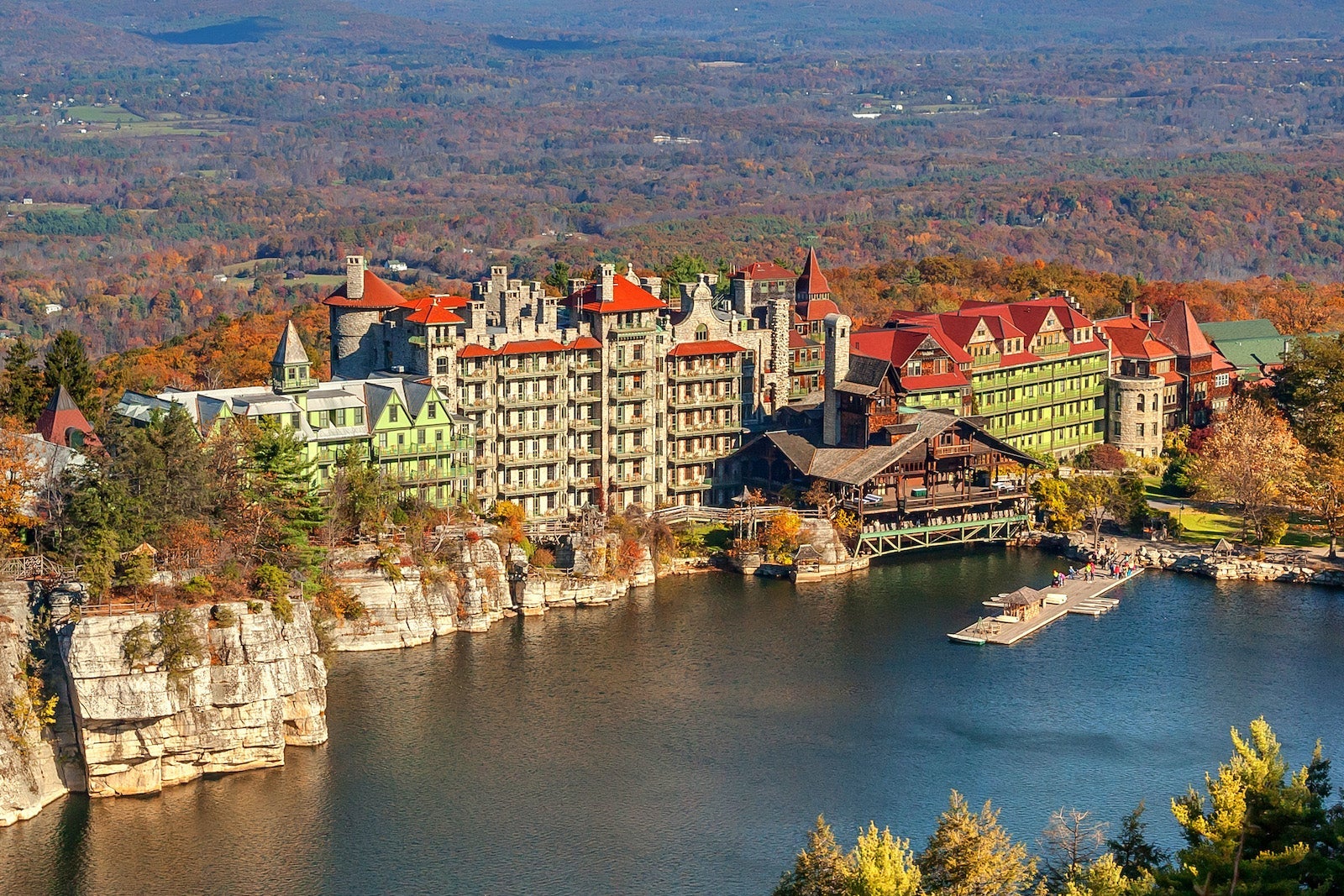 aerial photo of castle-like resort near lake with leaves changing colors