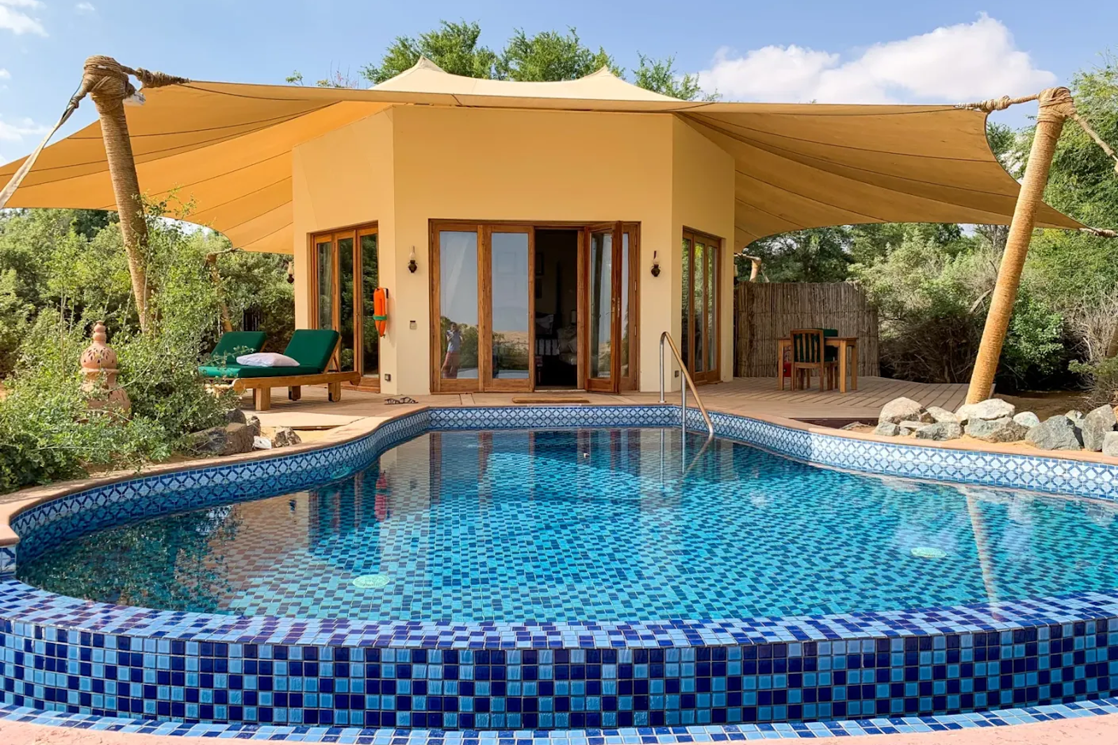 a small hut at a hotel sits behind a pool