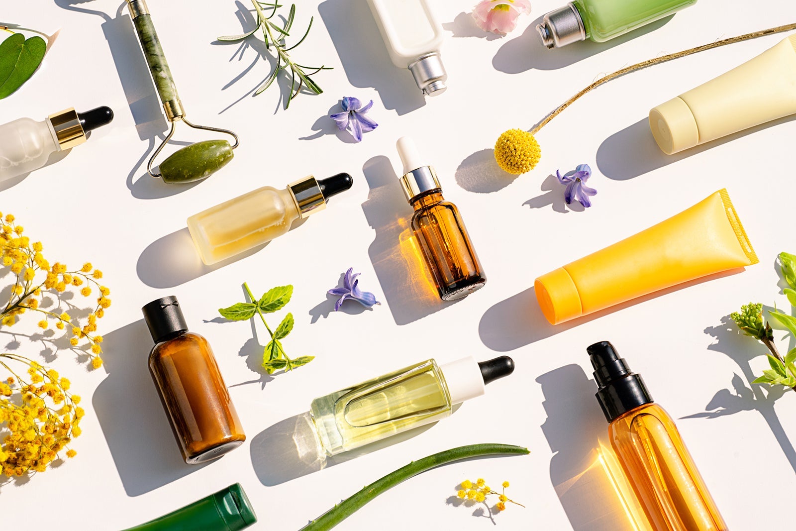 Photo lay of various beauty products including lotions, perfumes and flowers.