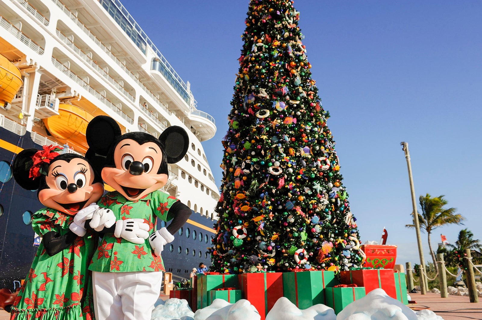 Mickey and Minnie in front of a Christmas tree on a cruise ship dock