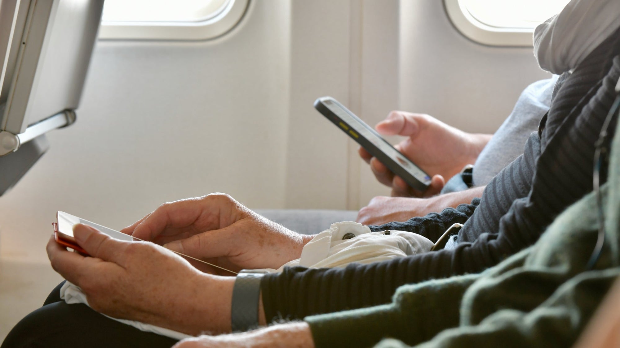 Older person using smartphone on plane