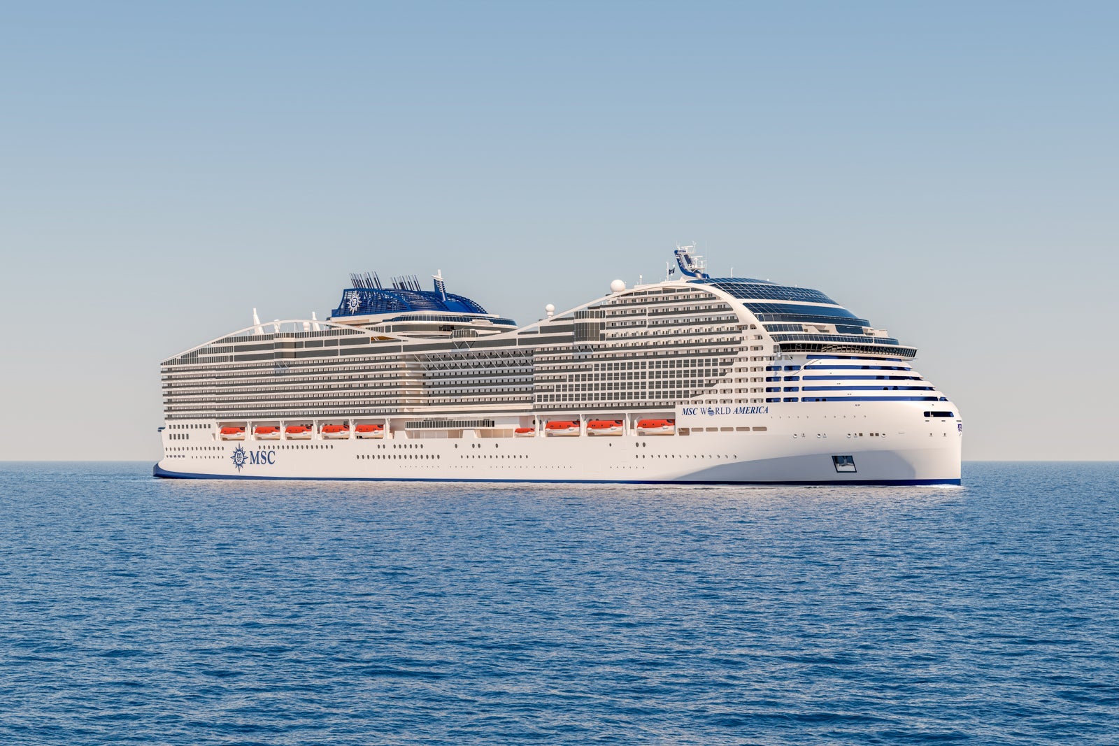 MSC World America anchored offshore in the middle of blue water with blue sky behind it