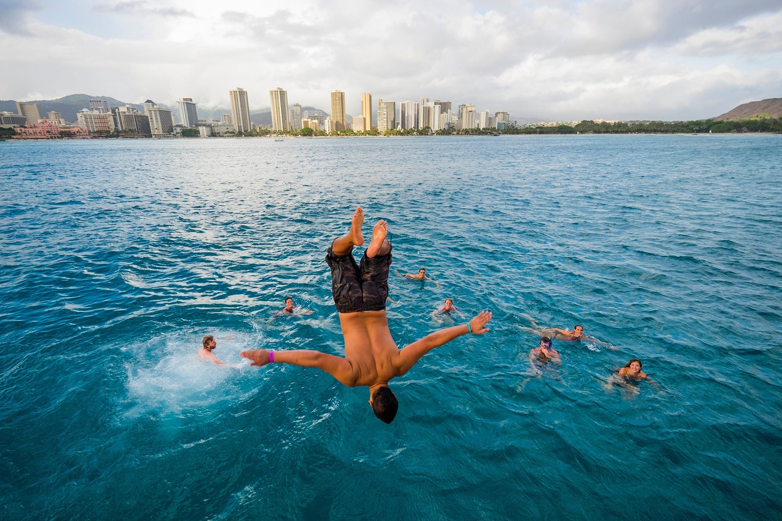 Man doing blackflip into the blue ocean
