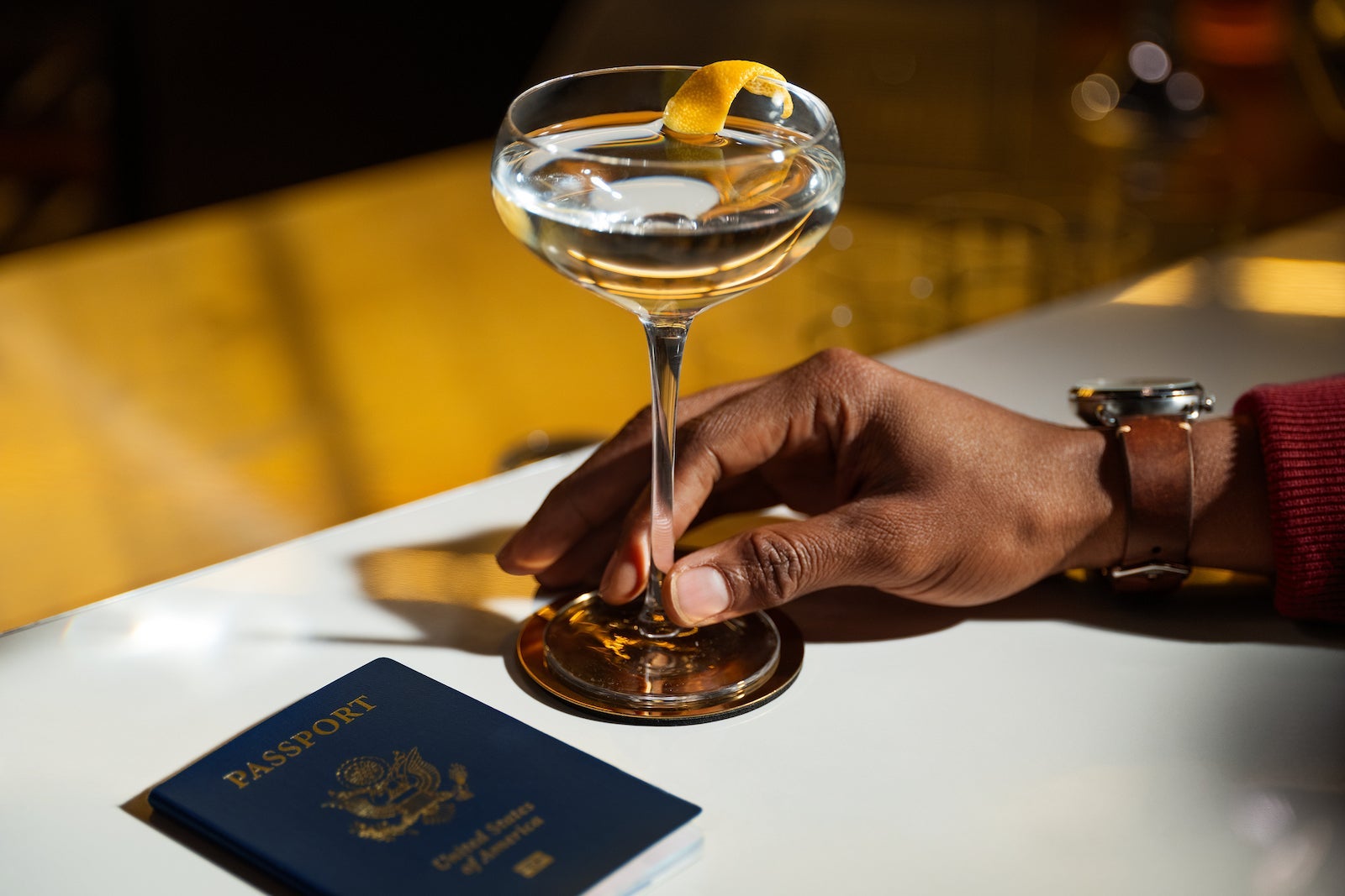 A hand holds a drink next to a passport