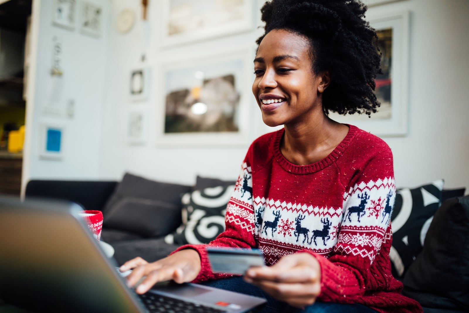 African American woman shopping online from her home office during winter holidays, holding a credit card
