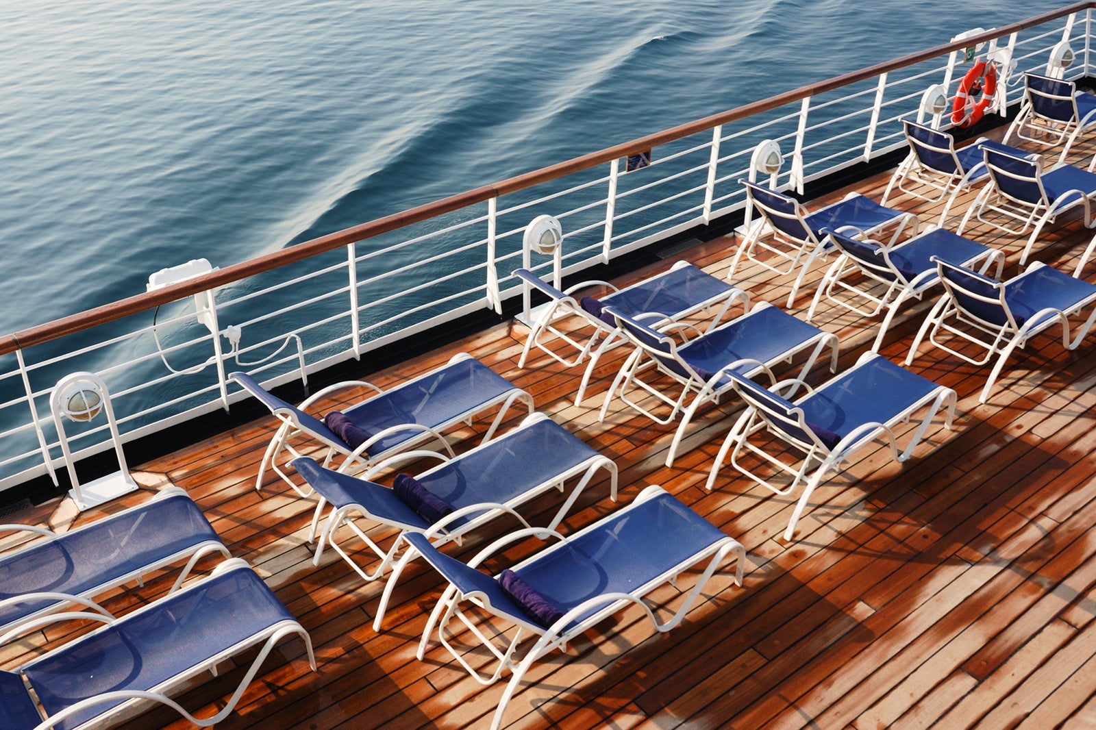 Rows of deck chairs on a cruise ship pool deck near the railing
