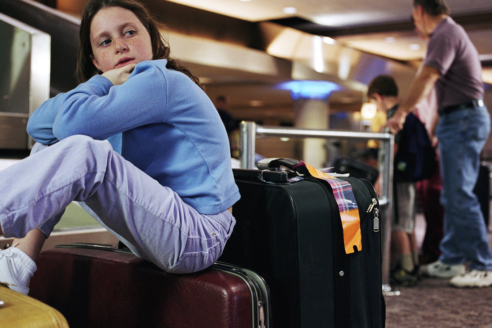 a child sits on a suitcase while waiting for a delayed flight