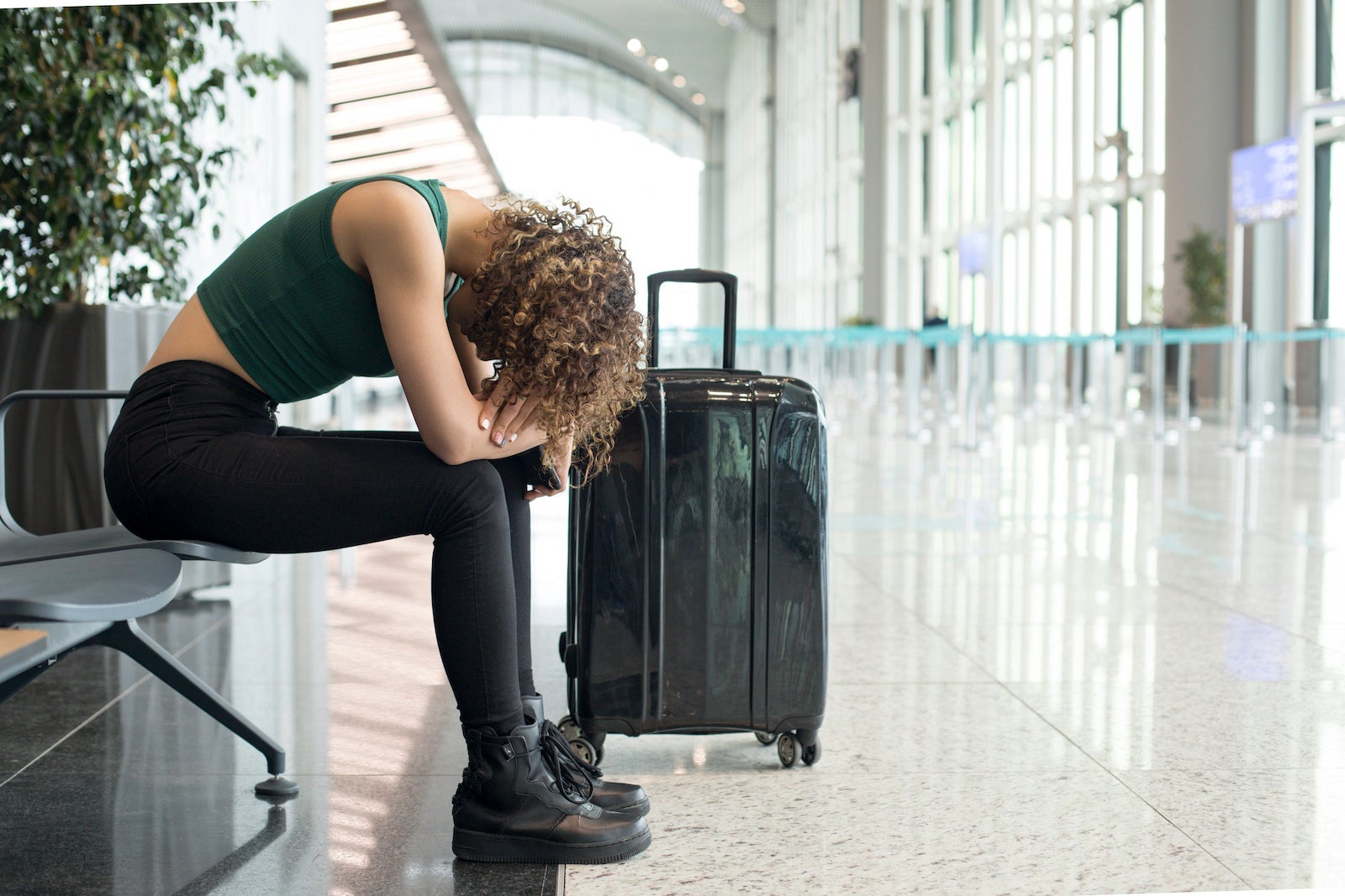 a frustrated person with their head down waits in an airport