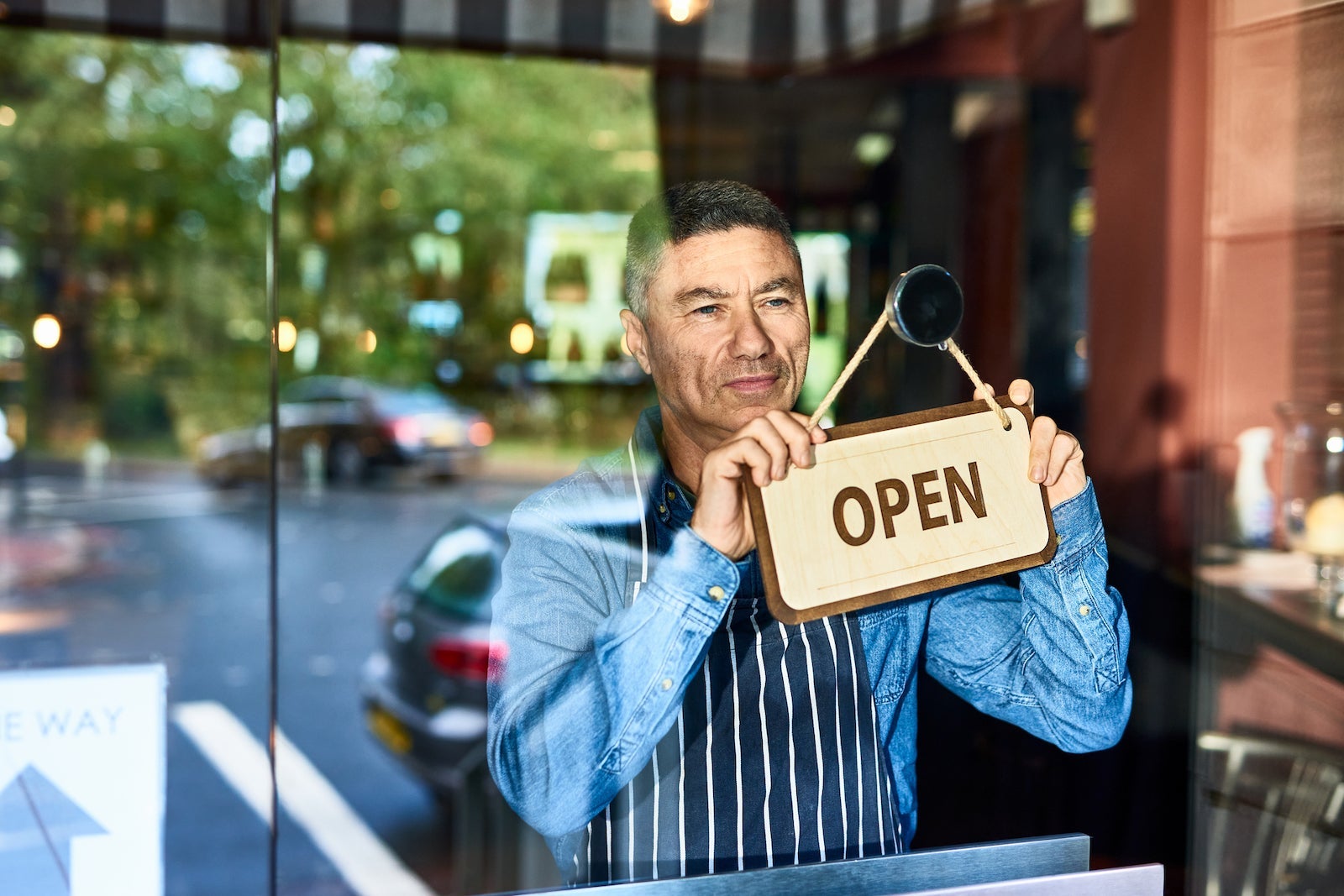 A business owner hangs an "open" sign on the door