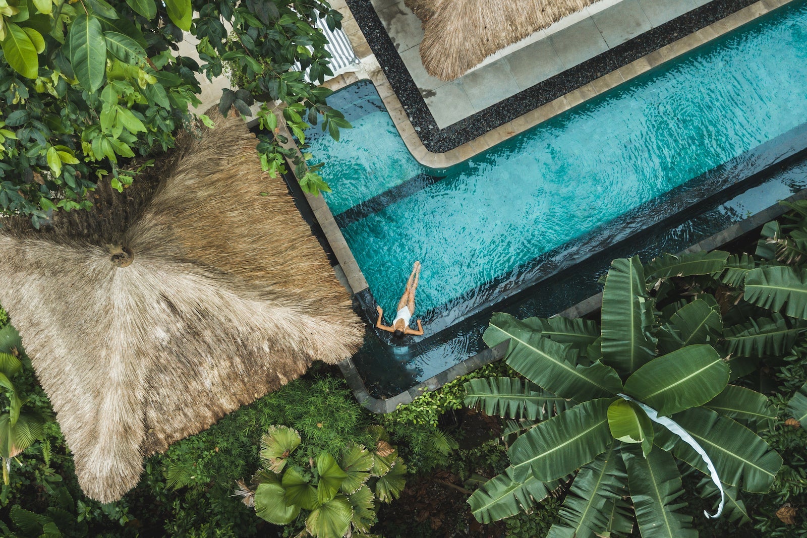 Woman enjoying alone in luxury swimming pool, drone view from above.
