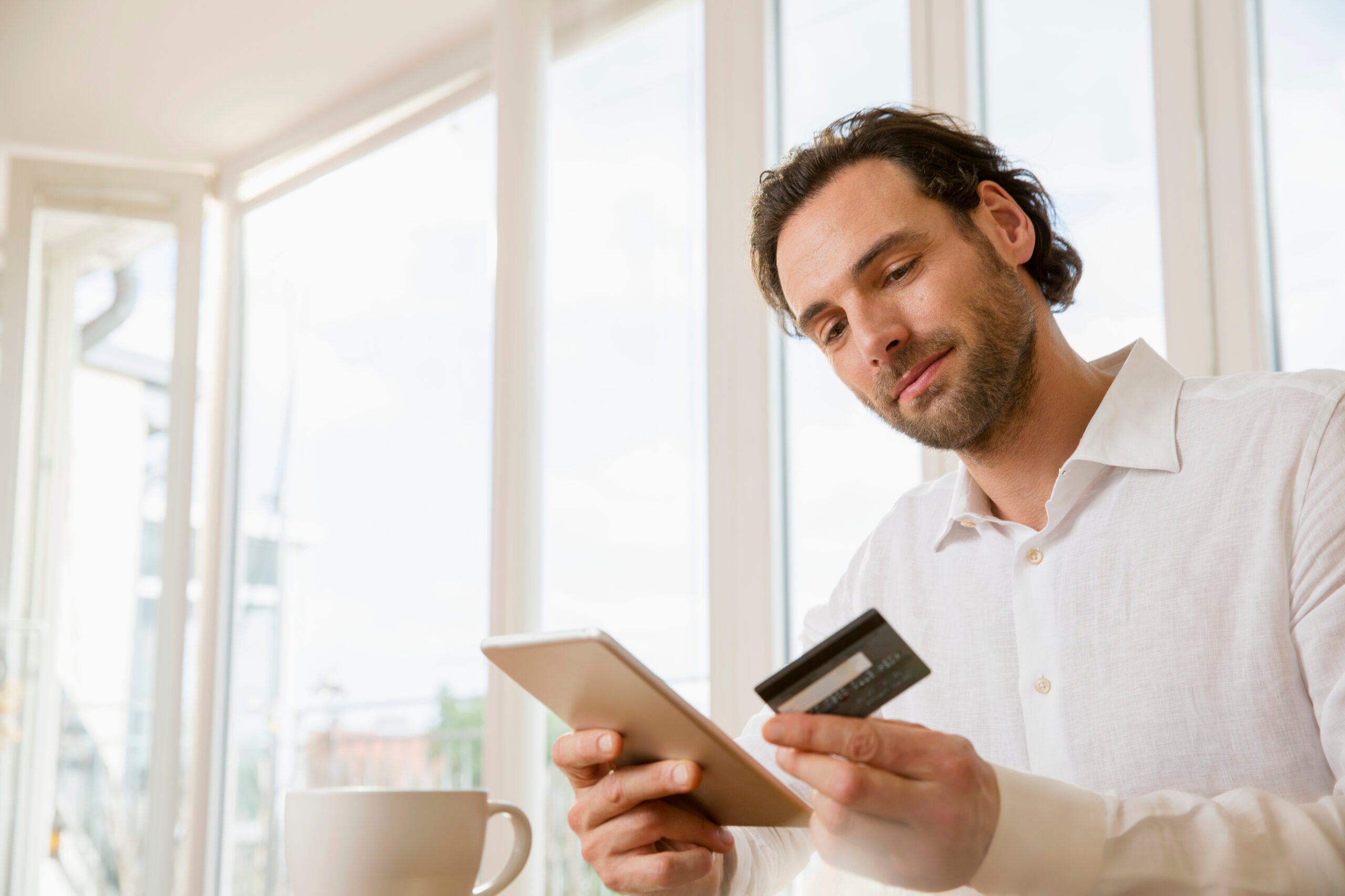 a man reads information about his credit card while sitting in a brightly-lit room