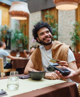Young Man Paying for Meal at Restaurant