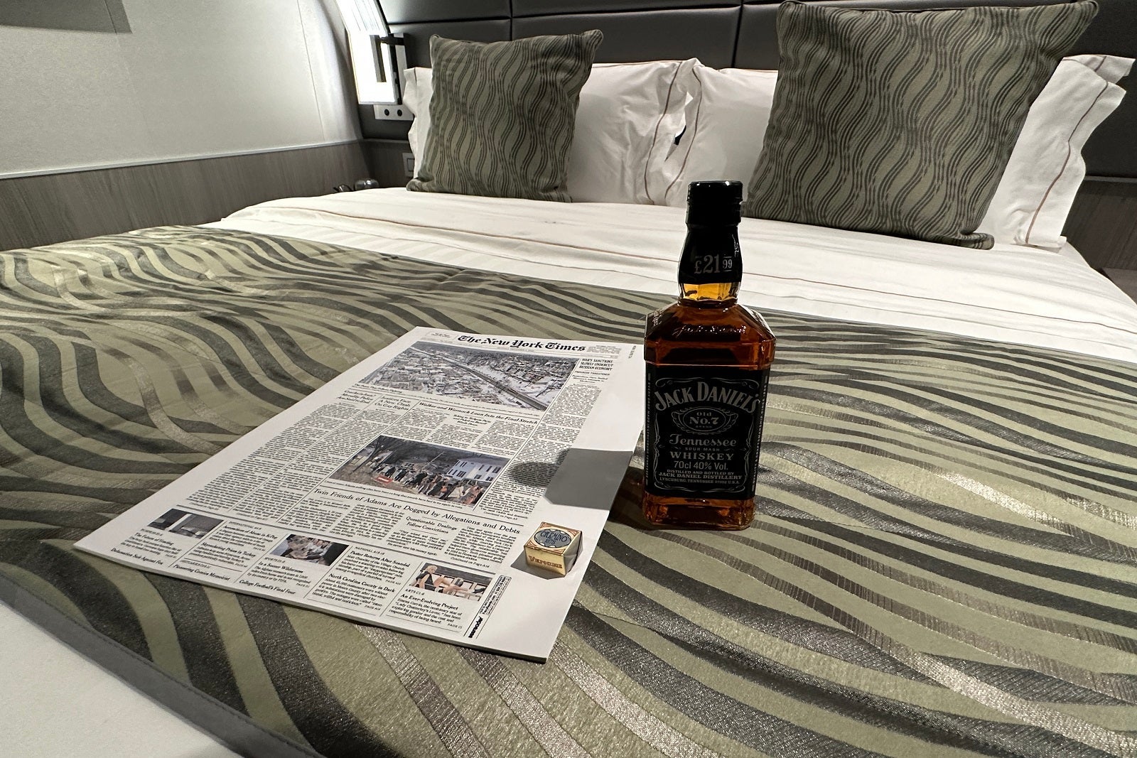 Newspaper and bottle of Jack Daniels on a cruise ship bed
