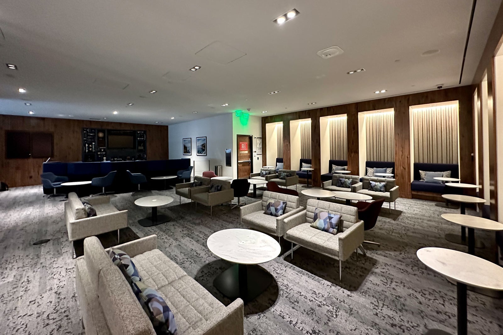 a spacious airport lounge with many lounge chairs, tables and work stations