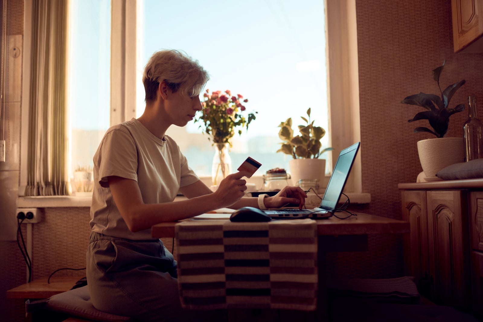 in a poorly-lit room, a person sits at a table reading about credit cards on a computer