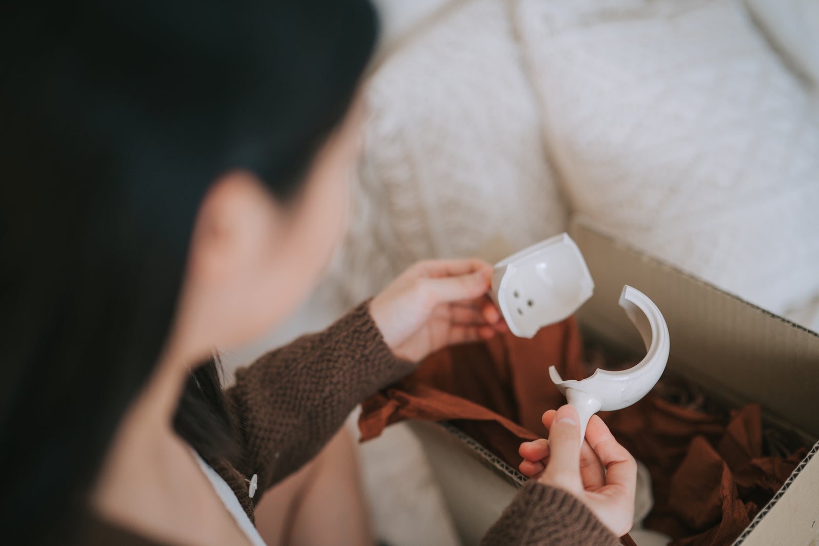 an unseen person removes a broken vase from its box