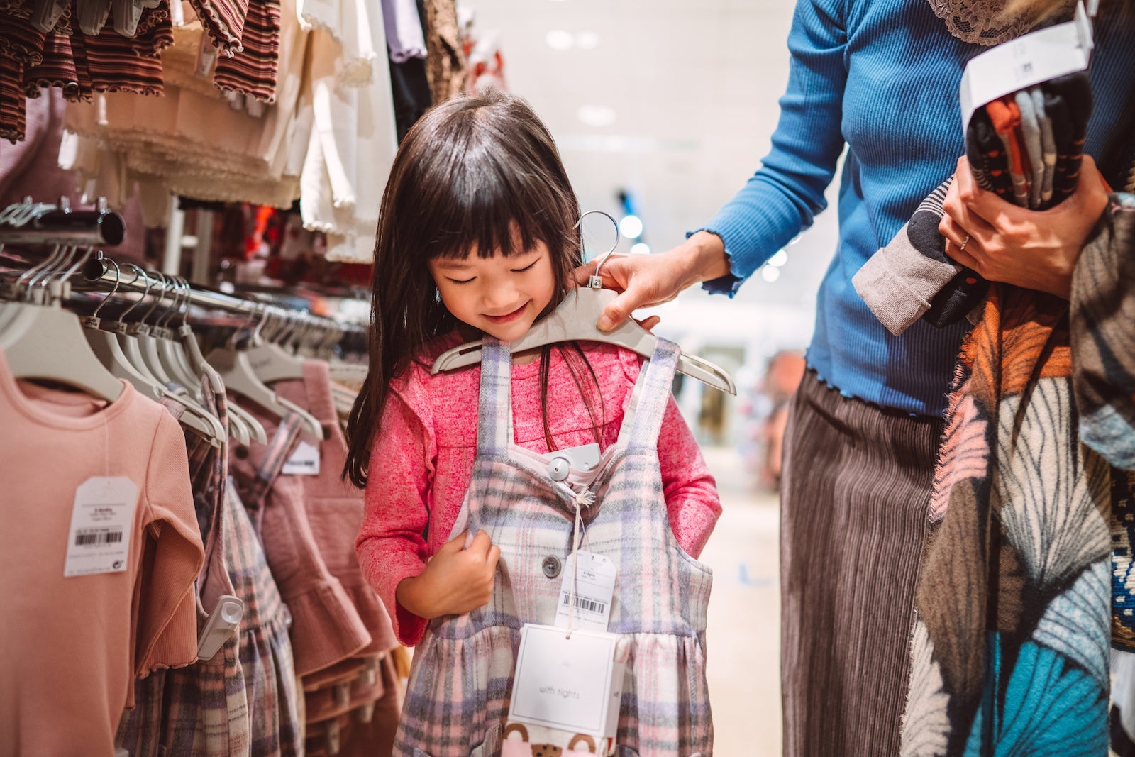 a parent holds a dress against a child to see if it will fit