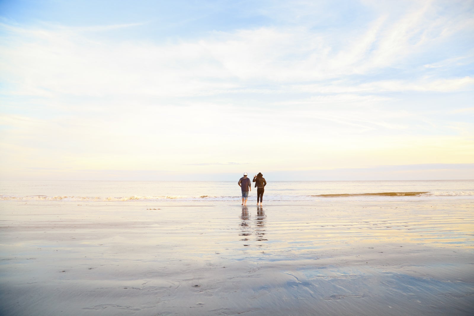 Couple, man and woman standing on ocean beach on sunset