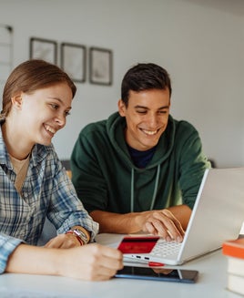 Two people in front of a laptop with a credit card