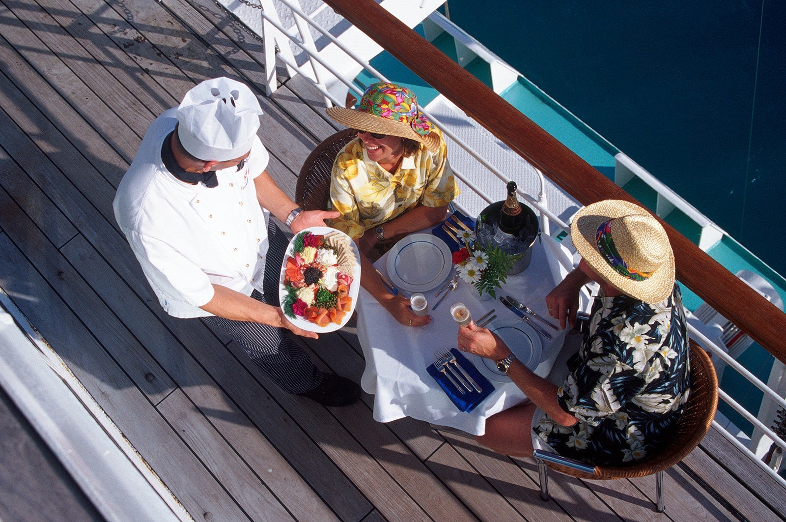 Waiter serving couple dining on cruise ship by railing