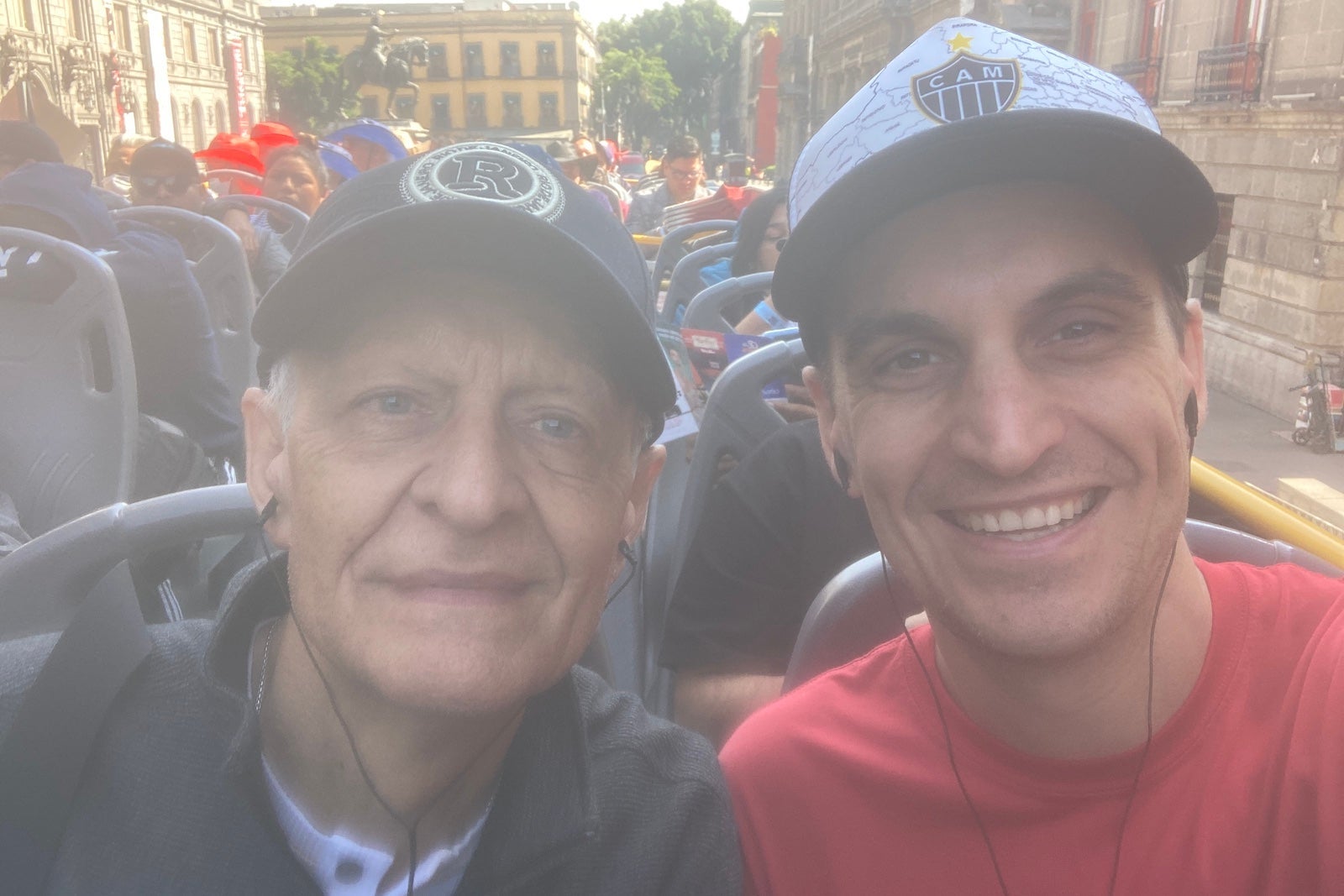 a father and son on the top level of a hop-on/hop-off bus