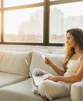 Young Woman relaxing on sofa and Shopping Online With Credit Card and Laptop